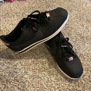 Black Nike Cortez sneakers with rose gold